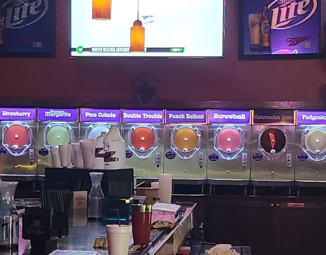 The row of frozen daiquiri machines under purple flavor labels