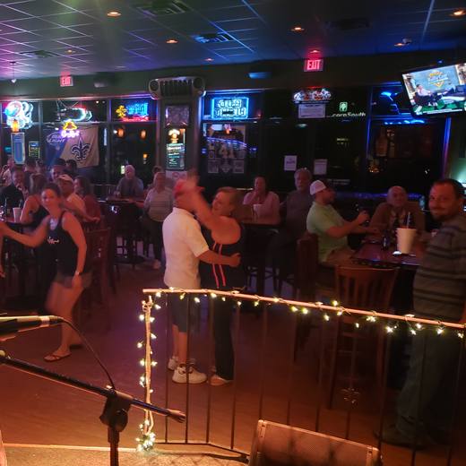 Karaoke night on the stage, string lights on the rail and people dancing