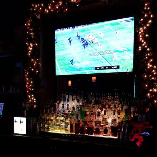 The game on the big TV, wrapped in string lights over the bottles