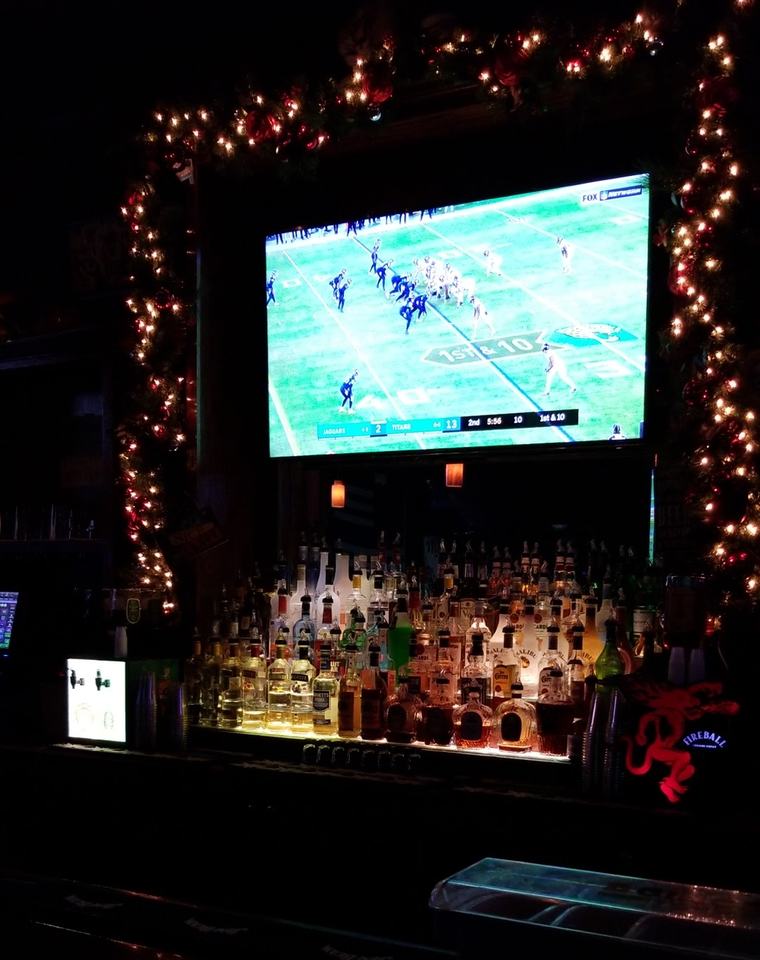 A football game on the big TV over the back bar, framed in string lights