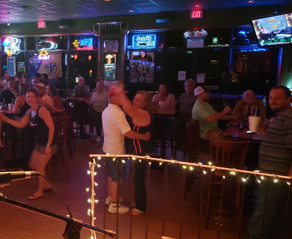 Karaoke night with string lights on the stage rail and people dancing